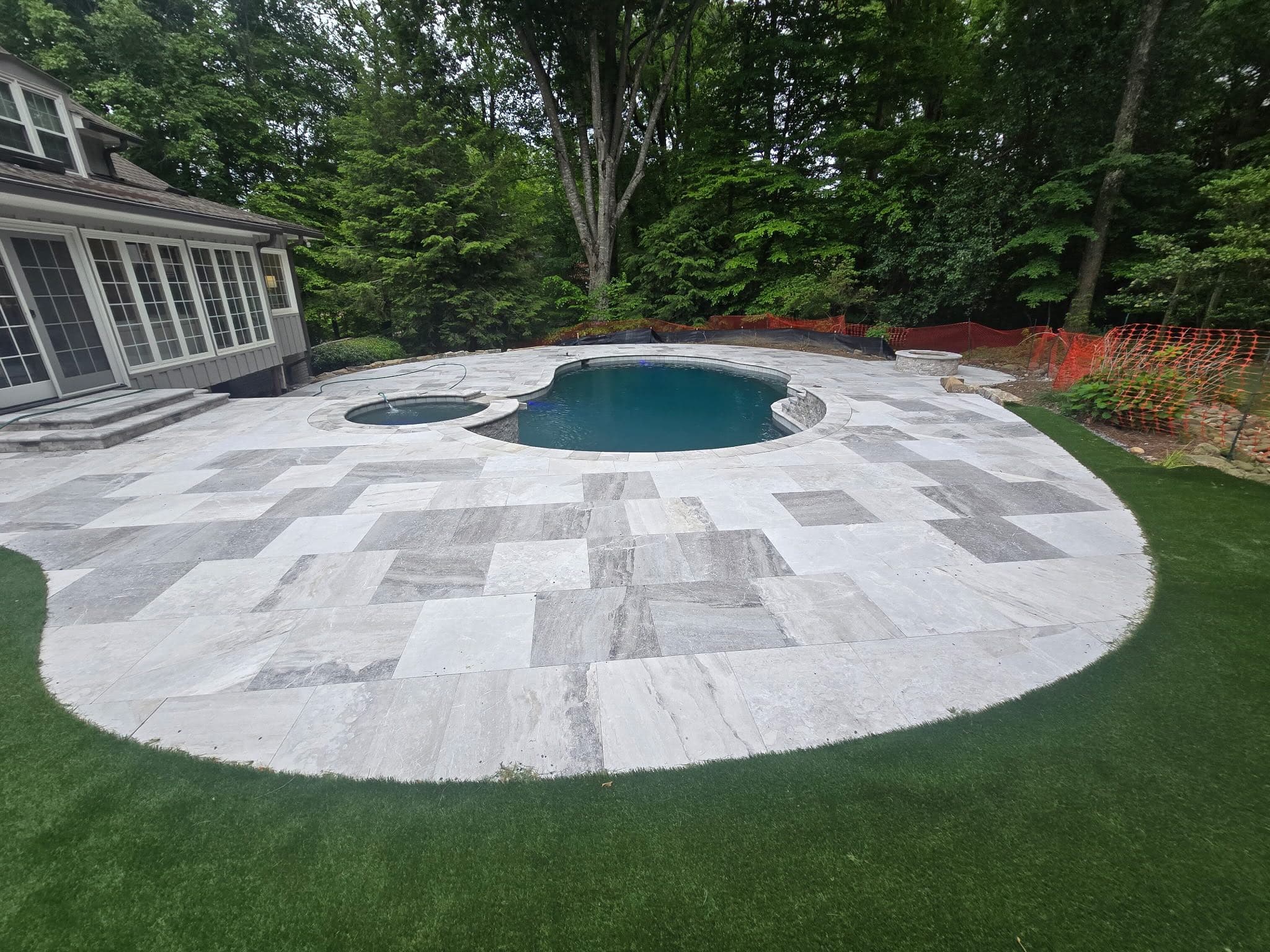 Aerial view of freeform pool with travertine paver deck and synthetic turf