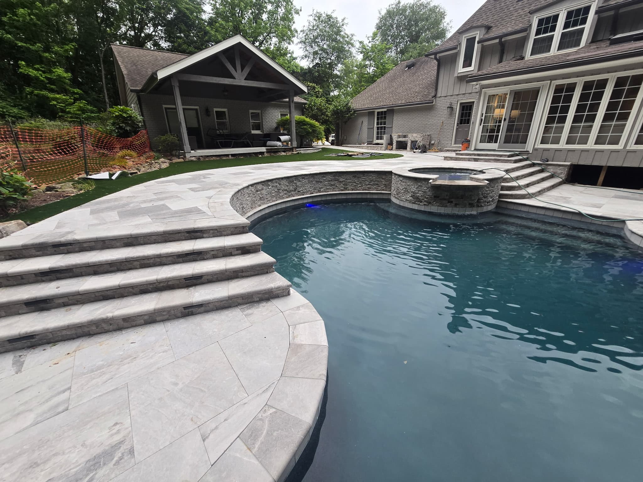 Raised spa with stone veneer and curved travertine deck steps