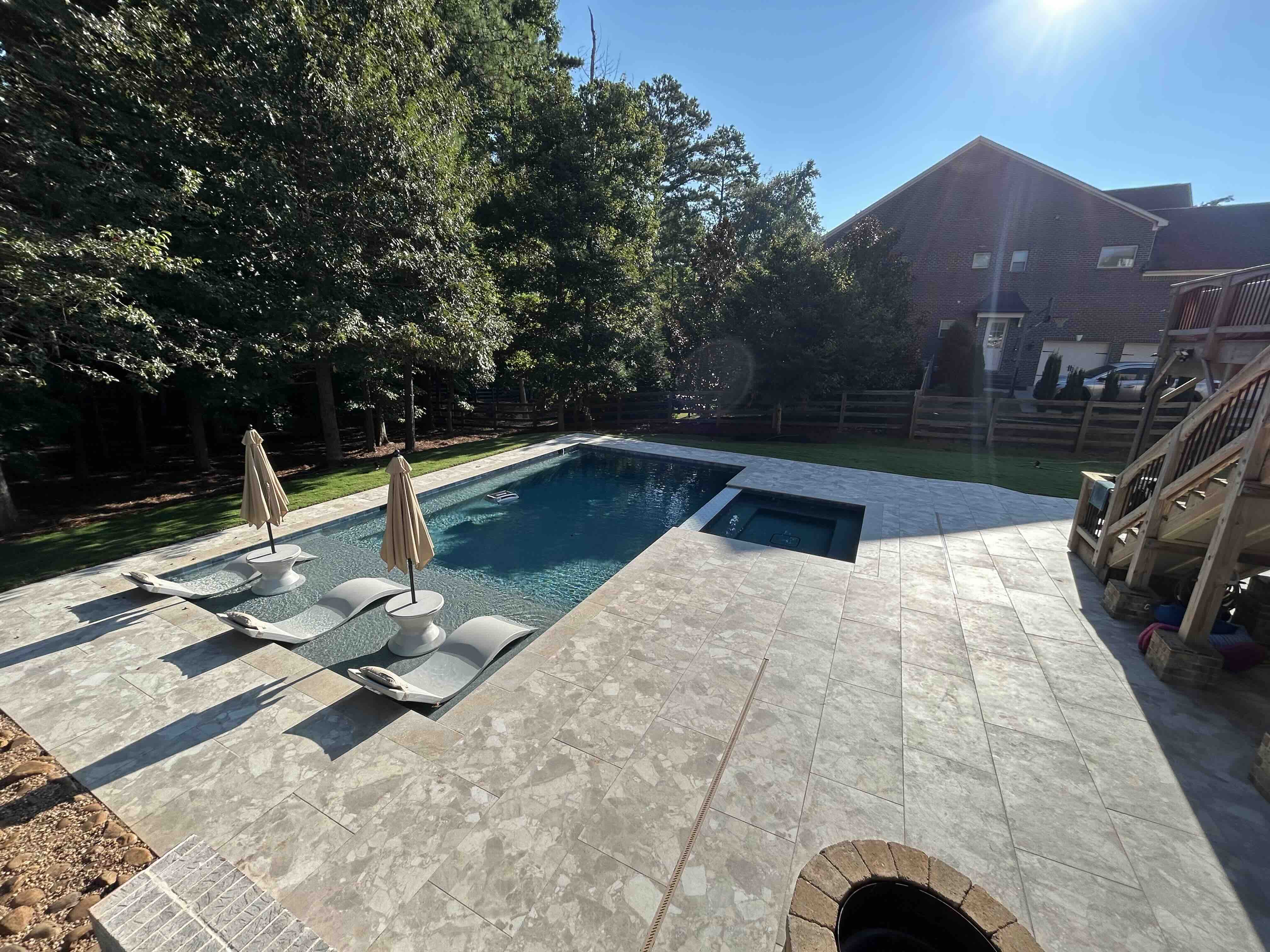 Luxury custom pool with sun shelf, spa, and travertine decking built by White Glove Construction in Metro Atlanta