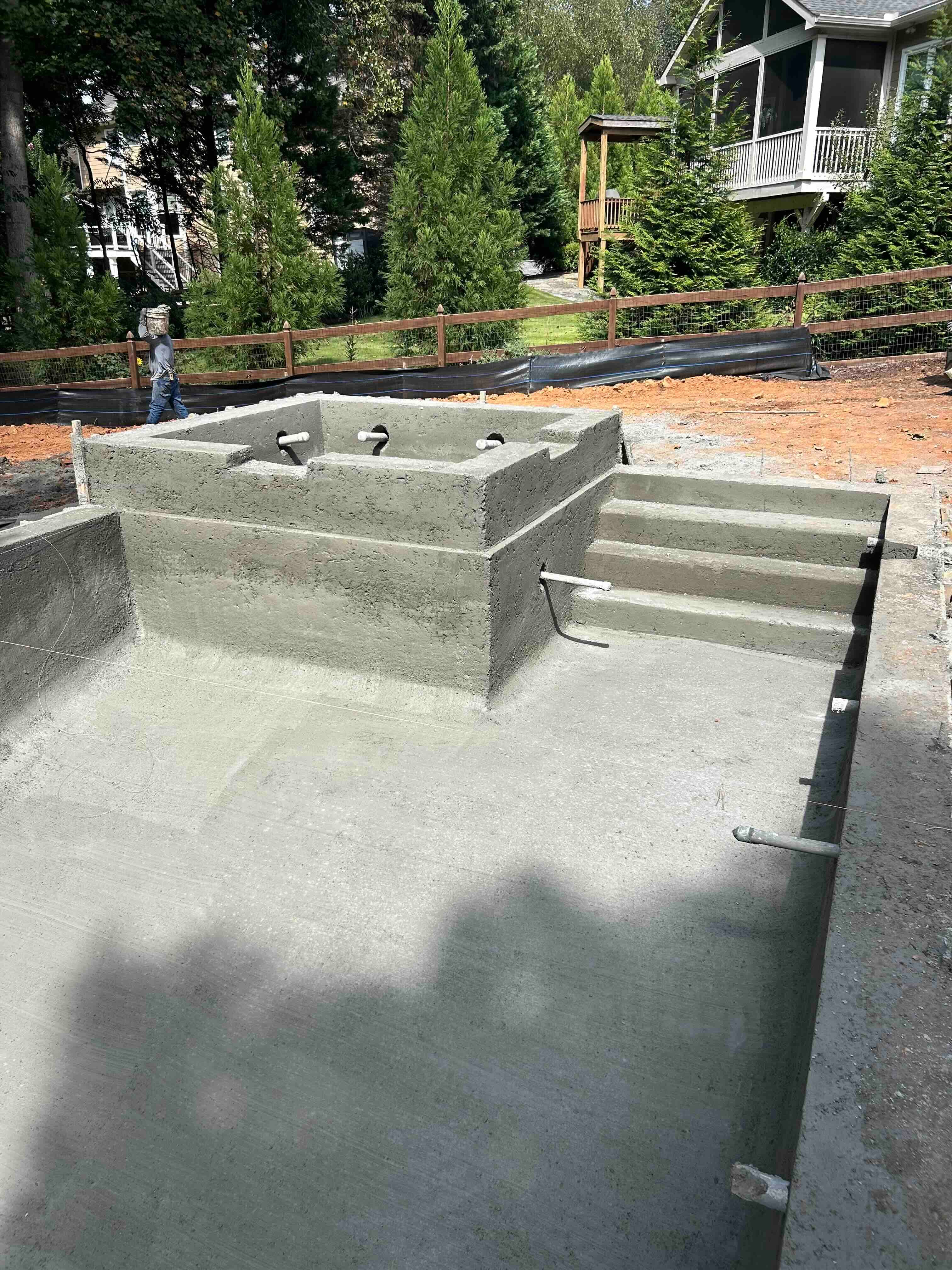 Fresh concrete pool shell with a raised spa and integrated steps.