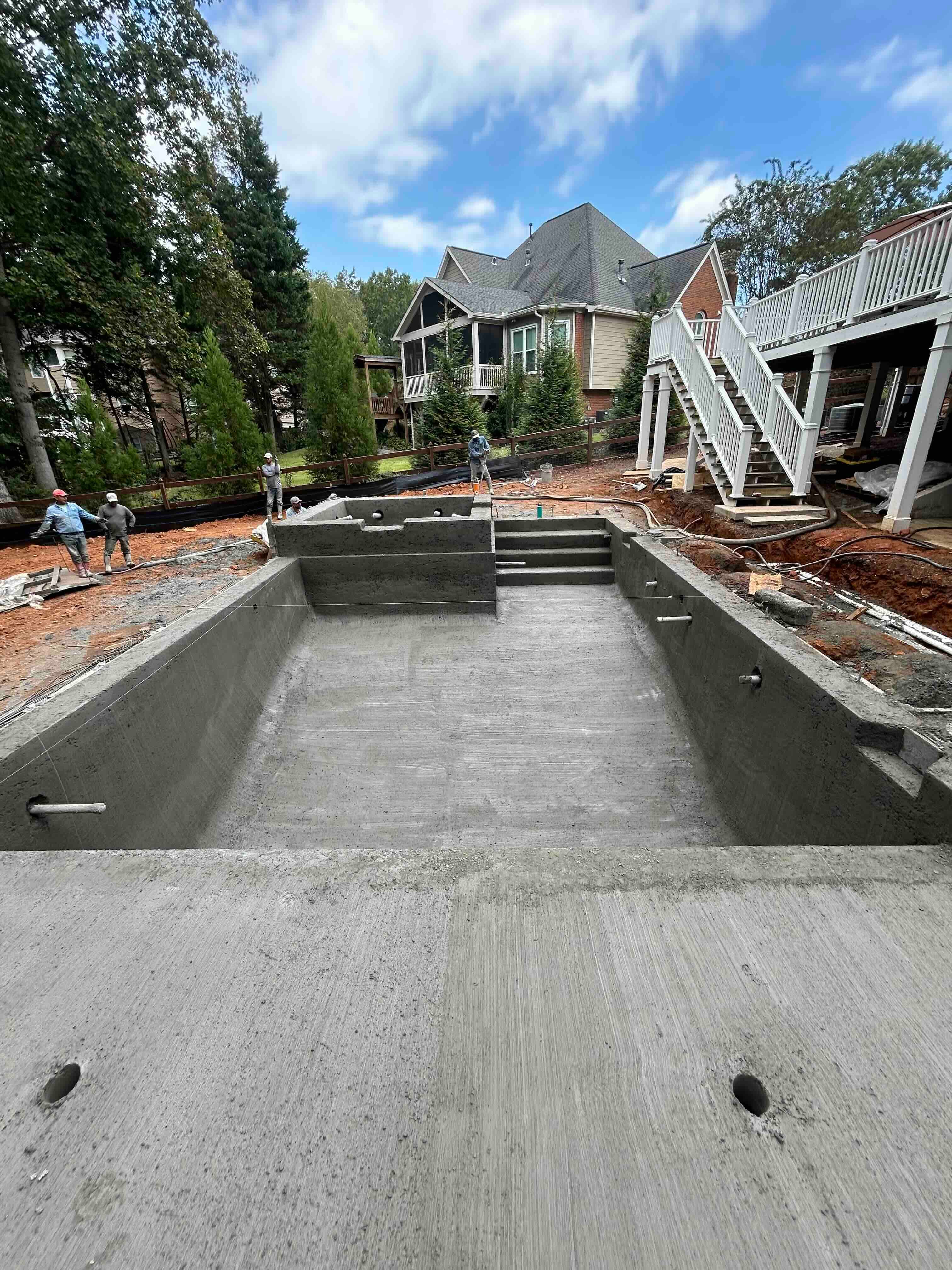 Fresh concrete pool shell with a raised spa and integrated steps.